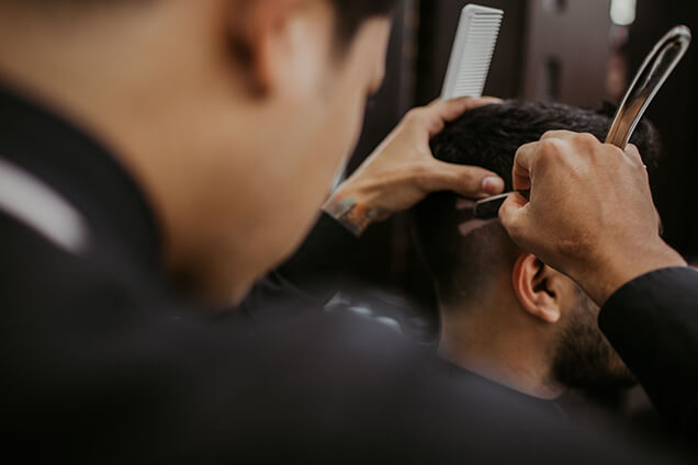 a barber styling a man's hair using a razor