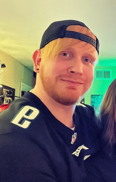 person in a black jersey and cap, standing indoors under green lighting